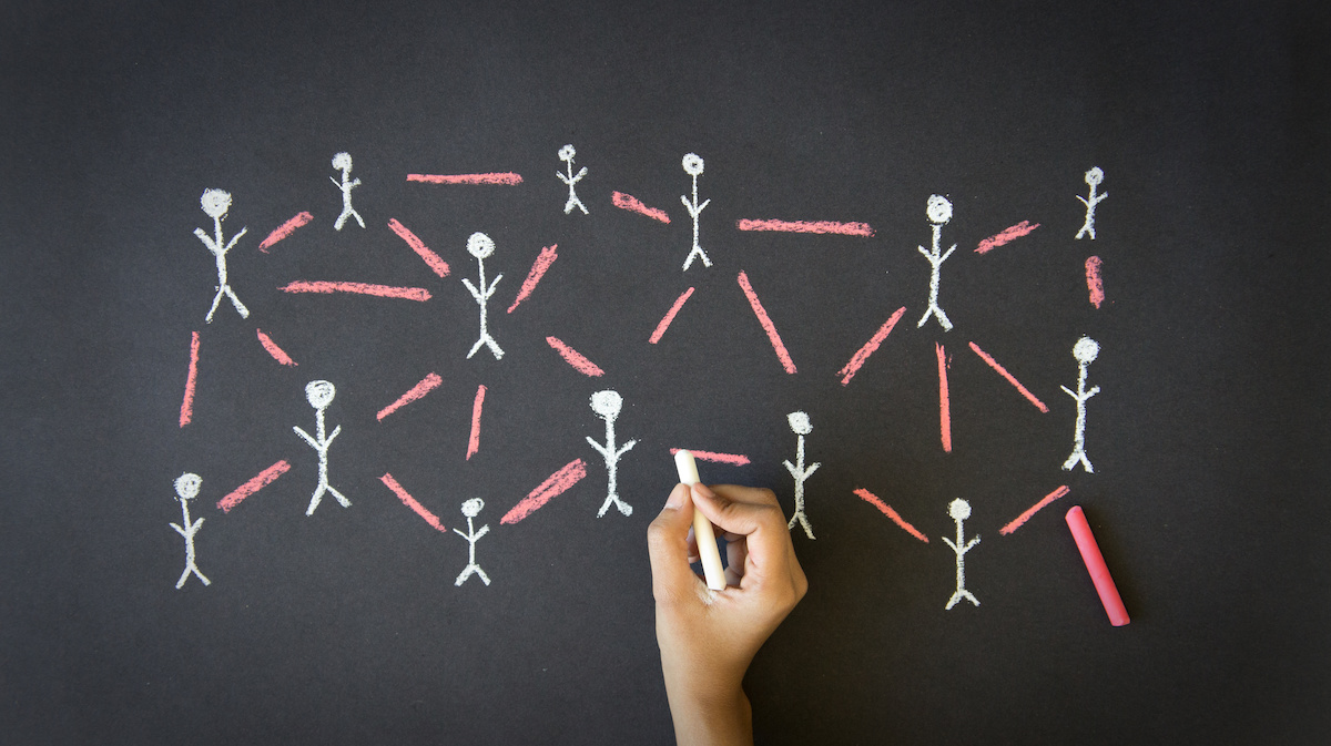 Person drawing a People Network illustration with chalk on a blackboard.