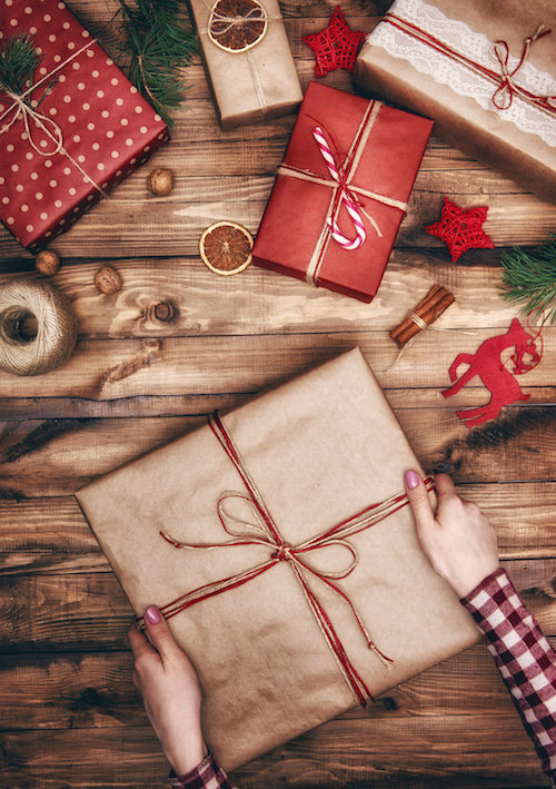 Merry Christmas and Happy Holidays! A woman prepares Xmas gifts. Baubles, presents, candy with christmas ornaments. Top view. Christmas family traditions.